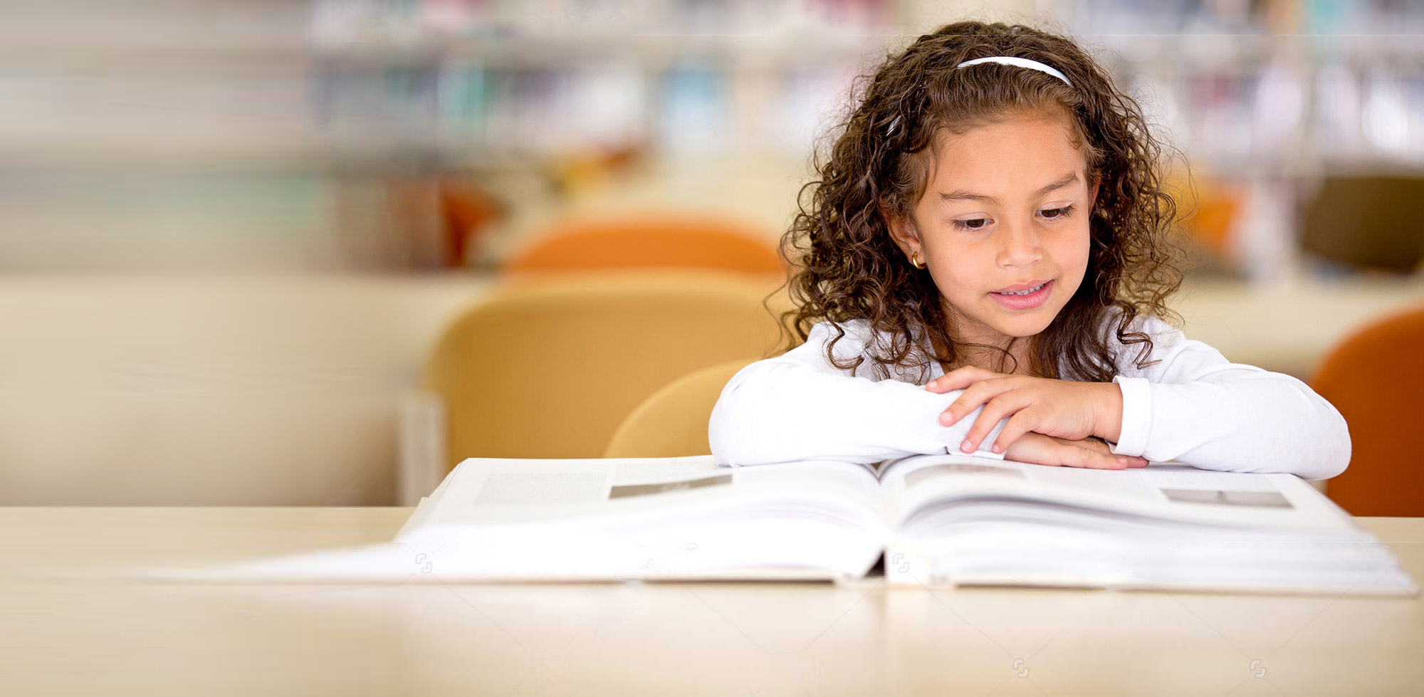stock-photo-young-school-girl-reading-a-book-at-the-library-120103876V2